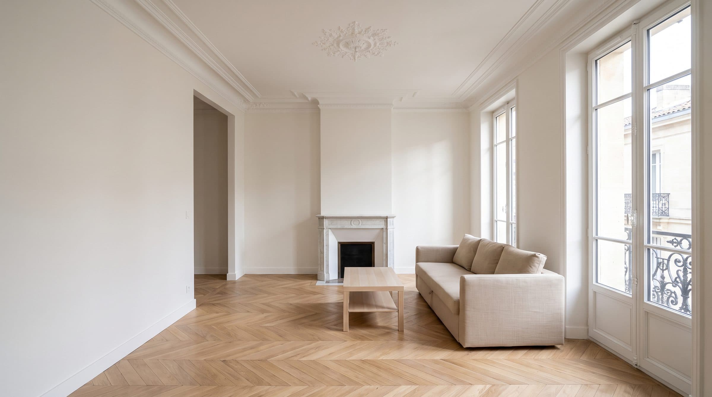 Le même séjour après rénovation : parquet en point de Hongrie, murs lisses, cheminée et moulures conservées